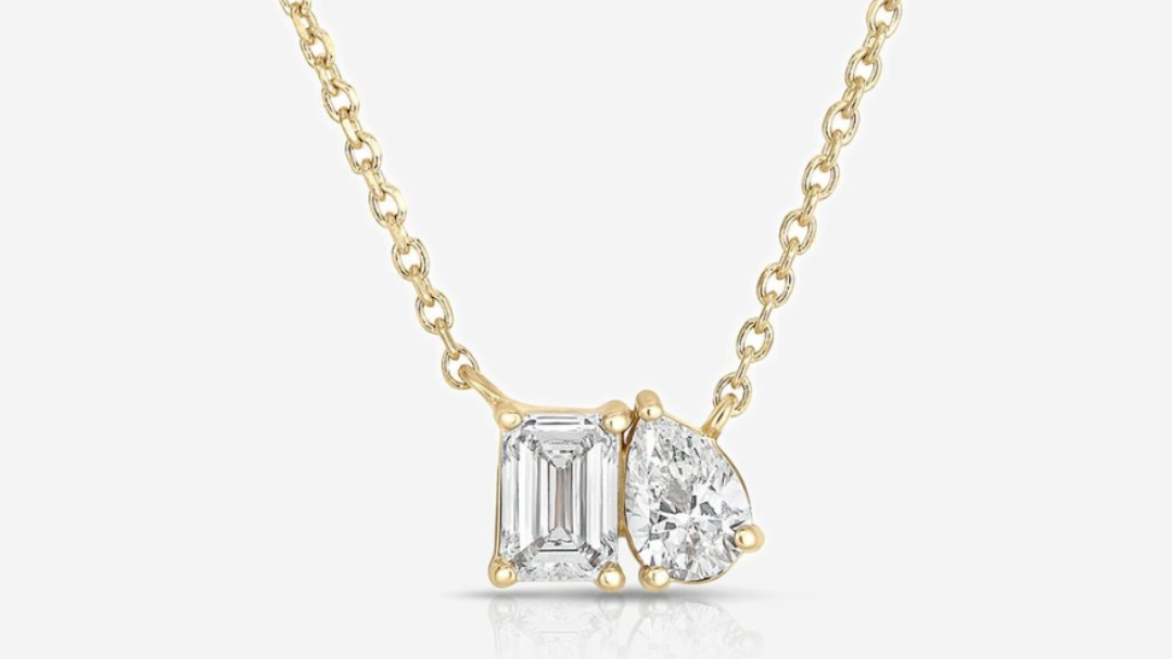 Gold necklace with two diamond pendants on a white background